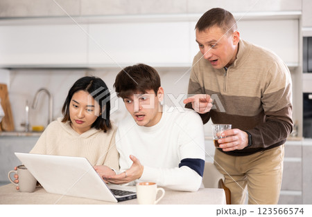 Friendly family watches something together on the Internet or video chats via laptop 123566574