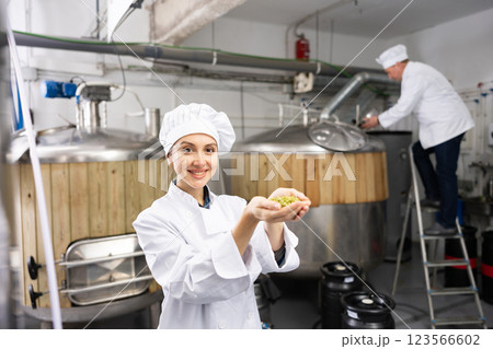 Woman brewer holding fresh hops in her hands on the territory of brewery 123566602