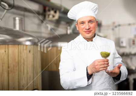 Brewer with glass filled with fresh hops at brewery Brewer with glass filled with fresh hops at brewery 123566692