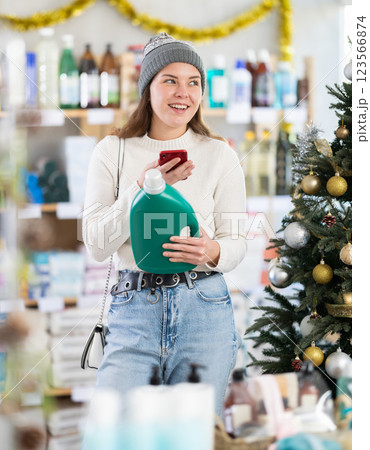 Young woman scanning QR-code on detergent in store during Christmas Young woman scanning QR-code on detergent in store during Christmas 123566874