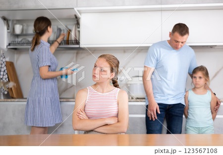 Aggrieved teenage girl listening to reprimand of father in kitchen Aggrieved teenage girl listening to reprimand of father in kitchen 123567108