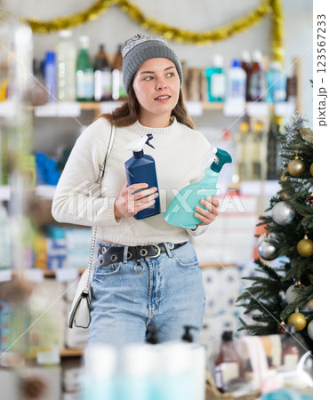 Woman buying cleaning sprays on Christmas tree background 123567233