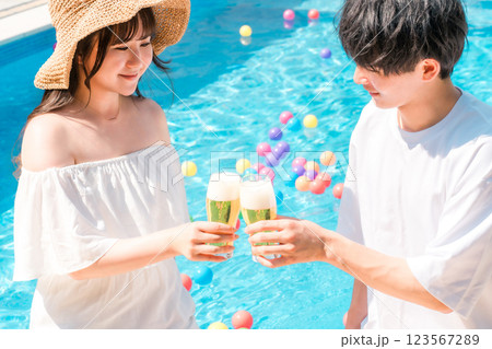 バカンス・リゾートホテルのプールサイドでビールグラスで乾杯するカップル 123567289