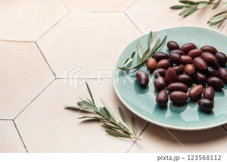 Kalamata olives with olive branches served on a modern plate Kalamata olives with olive branches served on a modern plate 123568112