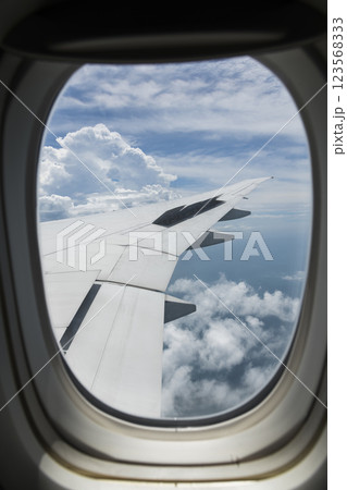 View of the plane's wing and beautiful clouds through the window during the flight. View of the plane's wing and beautiful clouds through the window during the flight. 123568333
