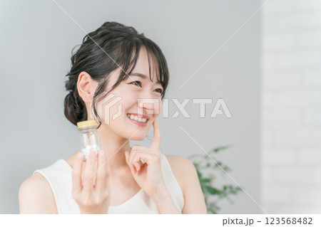 薬・サプリメントの瓶を持つ笑顔のアジア人女性 123568482