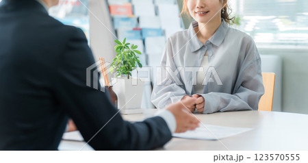 商談のテーブルで営業マンの話を聞く女性客 商談のテーブルで営業マンの話を聞く女性客 123570555