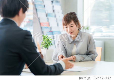 商談のテーブルで営業マンの話を聞く女性客 123570557