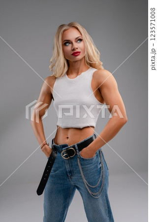 Fitness woman poses confidently in stylish lingerie-inspired sportswear Fitness woman poses confidently in stylish lingerie-inspired sportswear 123571008