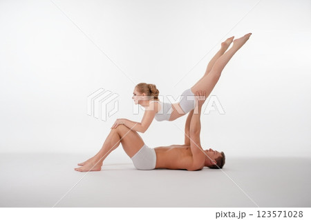 Couple performs acrobatic routine showcasing strength and balance in a studio Couple performs acrobatic routine showcasing strength and balance in a studio 123571028