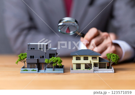 住宅模型とルーペを持つスーツ姿のミドル男性ビジネスマン 123571059