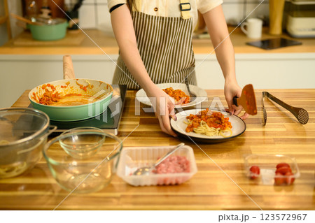 Young woman preparing a homemade pasta dish on wooden countertop Young woman preparing a homemade pasta dish on wooden countertop 123572967