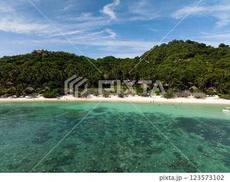 A hill with dense greenery overlooks a clear sea and sandy beach with coral reef. Koh Tao, Thailand. 123573102