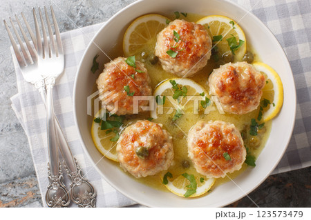 Chicken meatballs are finished with a velvety piccata sauce complete with lemon, white wine, and capers closeup. Horizontal top view Chicken meatballs are finished with a velvety piccata sauce complete with lemon, white wine, and capers closeup. Horizontal top view 123573479