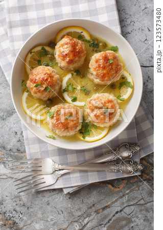 Chicken piccata meatballs with a delicious sauce of lemon, capers, white wine, and butter closeup in the plate. Vertical top view 123573480