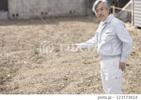 土地と作業服の男性 123573614