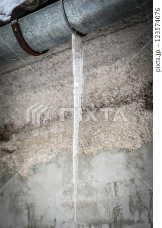 Long Icicle Hanging from a Metal Gutter in Winter. Long Icicle Hanging from a Metal Gutter in Winter. 123574076