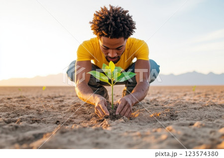 Young man planting trees in a desert to restore the environment and combat deforestation 123574380