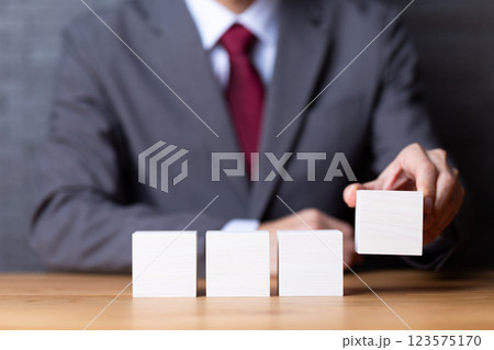 4つの白い木のブロックとスーツを着たミドル男性ビジネスマン 123575170