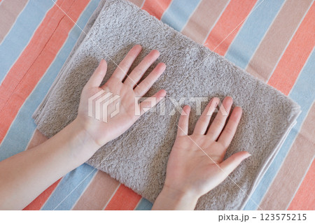 家の寝室で洗濯したタオルを整理している女性の両手の様子	 123575215