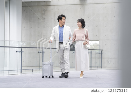 キャリーバッグを持って歩く笑顔の50代の夫婦　 123575315