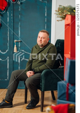 A man in an armchair against the background of a door decorated for New Year. A man in an armchair against the background of a door decorated for New Year. 123575371