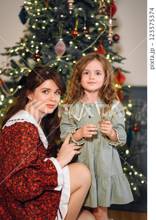 Beautiful mother and daughter at the Christmas tree. Beautiful mother and daughter at the Christmas tree. 123575374