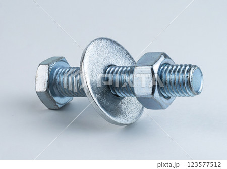A metal screw and washer on a light surface A metal screw and washer on a light surface 123577512