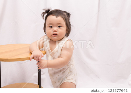 【テーブルでつかまり立ちをするツインテールの赤ちゃん】 123577641