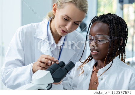 Waist up picture of a female teacher working with a girl in a school laboratory 123577673