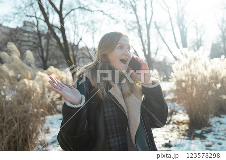 Portrait of happy smiling surprised Caucasian woman outdoors near building, using smartphone. Technology concept. 123578298