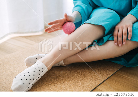 Woman using a textured massage ball for self-care and muscle relaxation. Wellness therapy, myofascial release, home relaxation 123578516