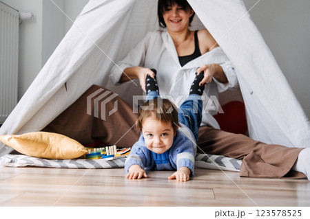 Mother playing with toddler in makeshift indoor tent. Early childhood development, role of play, motor skills, cognitive growth, parent-child interaction Mother playing with toddler in makeshift indoor tent. Early childhood development, role of play, motor skills, cognitive growth, parent-child interaction 123578525