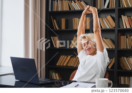 Middle aged senior woman relaxing stretching arms and body taking break from work on laptop at home. Older mature woman happy after work done satisfied by good result. Fatigue from long laptop usage Middle aged senior woman relaxing stretching arms and body taking break from work on laptop at home. Older mature woman happy after work done satisfied by good result. Fatigue from long laptop usage 123578680