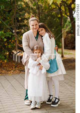 Mom hugging two daughters in the park. walks with children. Mom hugging two daughters in the park. walks with children. 123579382