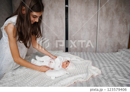 Newborn baby with his teen sister in a white dress on the bed in the bedroom 123579406