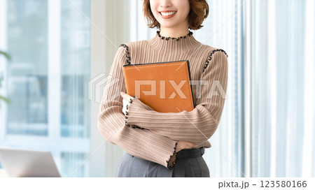 バインダーを持つ笑顔の女性・ビジネスウーマン バインダーを持つ笑顔の女性・ビジネスウーマン 123580166