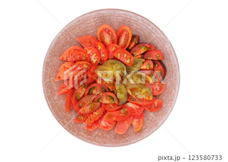 Tomatoes in a clay plate isolate on white background. Red sliced tomato in rustic red bowl. Food making. Top view. 123580733