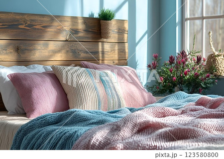 Rustic bedroom with a wooden headboard, soft pastel bedding, and natural sunlight filtering through the window 123580800
