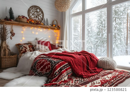Festive rustic bedroom with a cozy bed, red knitted blankets, decorative pillows, and a large window Festive rustic bedroom with a cozy bed, red knitted blankets, decorative pillows, and a large window 123580821