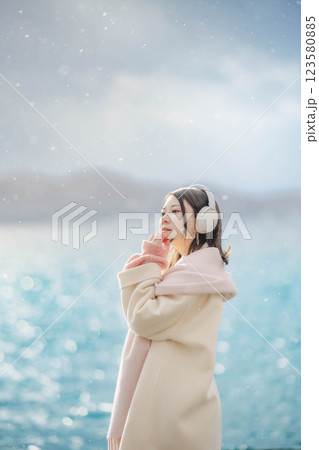 湖の波打ち際でヘッドホンで音楽を聴いている若い女性 123580885