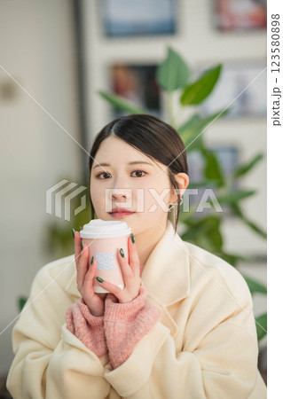 室内で飲み物を飲む若い女性 室内で飲み物を飲む若い女性 123580898