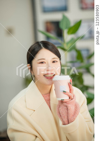 室内で飲み物を飲む若い女性 123580903
