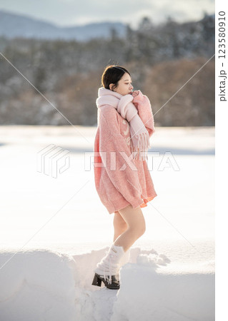 冬の温かい光の中にいるニット姿の若い女性 123580910
