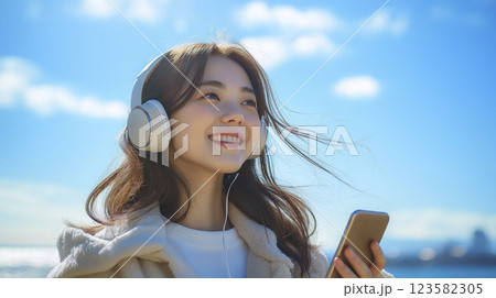 スマホを持ち風に吹かれながら音楽を楽しむ女性のイラスト「AI生成画像」 123582305