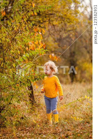 Little girl with curly hair enjoying autumn in a yellow shirt 123582931