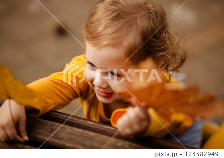Happy little girl in yellow shirt enjoying autumn nature Happy little girl in yellow shirt enjoying autumn nature 123582949