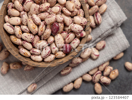 Wooden bowl full of dried pinto beans on napkin on gray top view. Traditional Latin American legumes Wooden bowl full of dried pinto beans on napkin on gray top view. Traditional Latin American legumes 123584407