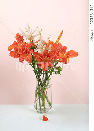 Abstract floral composition, background, minimal holiday concept with flowers, spring summer banner. Lily and chamomile flowers in a vase with shadows on a sunny table, postcard with space for text. 123584516