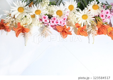 Abstract floral composition, background, holiday concept with flowers, spring and summer banner. Chamomile flowers, lilies and phlox on a sunny table, postcard with space for text. selective focus Abstract floral composition, background, holiday concept with flowers, spring and summer banner. Chamomile flowers, lilies and phlox on a sunny table, postcard with space for text. selective focus 123584517